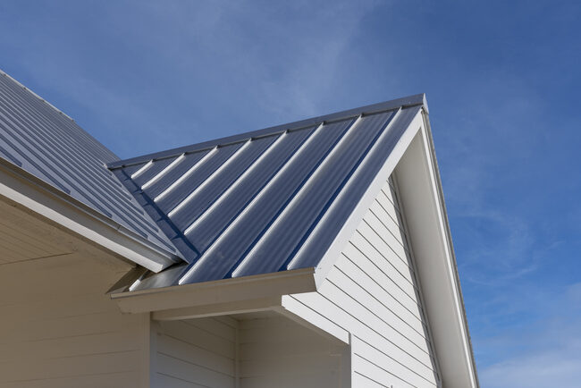 A black new roof and white siding of a house that is new and under construction.